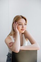 Pretty young woman sitting on chair and smiling at home.