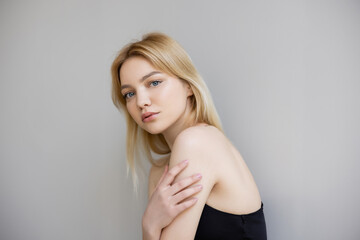 Fototapeta premium Blonde woman looking at camera isolated on grey.