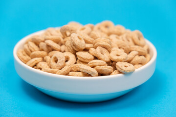Quick cereal breakfast in the form of rings on a plate on a blue background