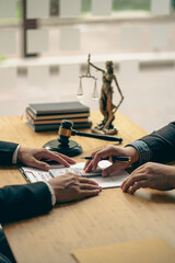 Businessman and lawyer man discussing legal matters and signing contract papers with judge's hammer with the goddess of justice in a team meeting at Law Concepts Office background and services.