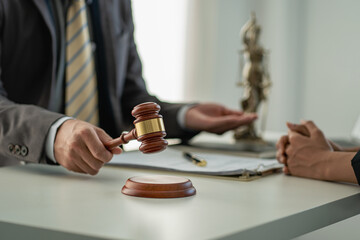 Businessman and lawyer man discussing legal matters and signing contract papers with judge's hammer with the goddess of justice in a team meeting at Law Concepts Office background and services.