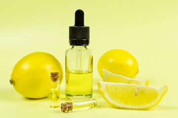 Essential oil of fragrant lemon in a transparent glass bottle with a pipette on a yellow background. Aromatherapy (against fatigue, headache, relaxation), spa, skin care.