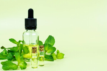 Essential oil of mint (peppermint) in two transparent glass bottles with a stopper and in a bottle...