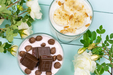 Multi-layered cottage cheese dessert with chocolate corn balls, yogurt and chocolate slices and banana dessert with cookies in a glass glass. Romantic breakfast. Top view.