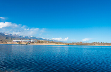 Sverny shore of Lake Issyk-Kul, Kyrgyzstan. View from the ship to the shore. Blue water of a mountain lake.