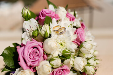 Composition with the bride's bouquet of pink roses and wedding rings visible from a high angle.