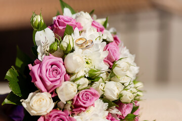 Close-up of the bride's bouquet of pink roses and wedding rings. Wedding.