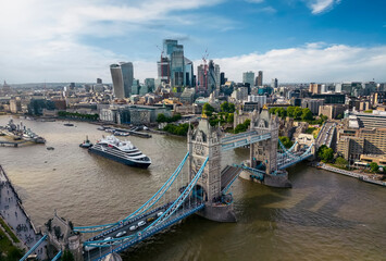 Panoramic aerial view of the cityscape of London, England, with the lifted Tower Bridge and a cruise ship passing under