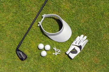 Poster Top view of golf equipment on green grass on a golf course. Flat lay of golf club, balls, glove, tees and cap © SDF_QWE