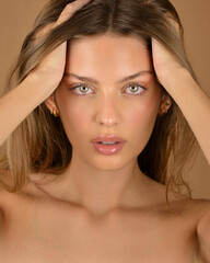 Hair and skin care. Close-up portrait of beautiful sensual young woman touching her pure face.