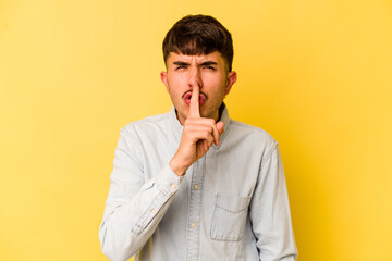 Young caucasian man isolated on yellow background keeping a secret or asking for silence.