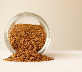 Roasted sesame seeds pouring from a jar. Space is left for expressive appearance, message or advertisement.