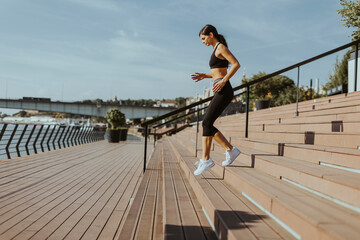 Young woman in sportswear exercising on a river promenade