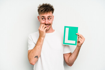 Young caucasian man holding L placard isolated on white background biting fingernails, nervous and very anxious.