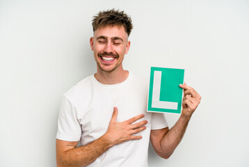 Young caucasian man holding L placard isolated on white background laughing and having fun.