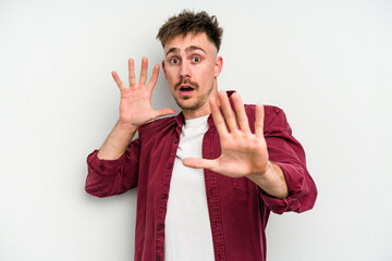 Young caucasian man isolated on white background being shocked due to an imminent danger