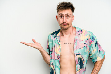 Young caucasian man isolated on white background showing a copy space on a palm and holding another hand on waist.