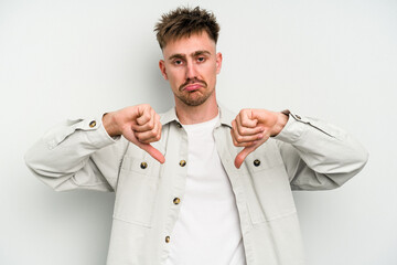 Young caucasian man isolated on white background showing a dislike gesture, thumbs down....