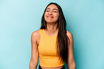 Obraz premium Young hispanic woman isolated on blue background laughs and closes eyes, feels relaxed and happy.