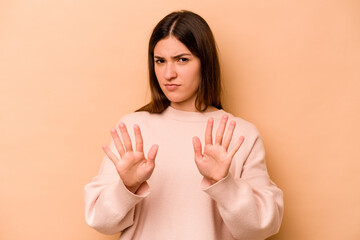 Young hispanic woman isolated on beige background rejecting someone showing a gesture of disgust.