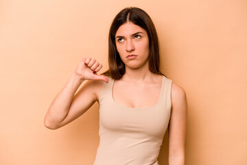Young hispanic woman isolated on beige background showing a dislike gesture, thumbs down. Disagreement concept.