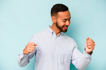 Young hispanic man isolated on blue background dancing and having fun.