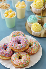 High angle view of donuts with sugar glaze on plate with cupcakes in background served on holiday table