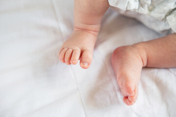 Small feet of a newborn baby on the bed, top view. The concept of motherhood, breastfeeding.
