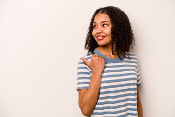 Young African American woman isolated on white background points with thumb finger away, laughing and carefree.