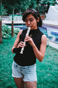 Muchacha tocando la flauta en parque