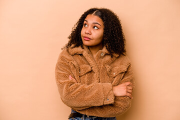 Young African American woman isolated on beige background dreaming of achieving goals and purposes
