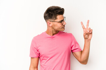 Young caucasian man isolated on white background joyful and carefree showing a peace symbol with fingers.