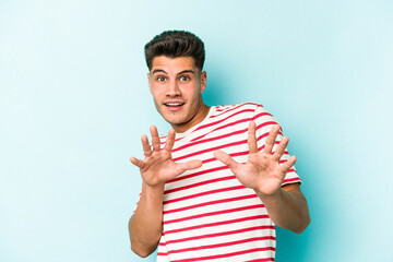 Young caucasian man isolated on blue background rejecting someone showing a gesture of disgust.