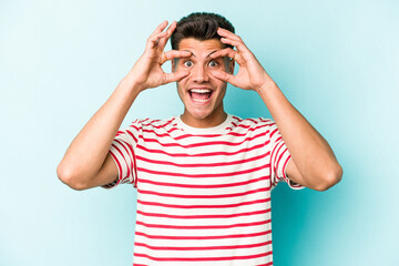 Fototapeta premium Young caucasian man isolated on blue background keeping eyes opened to find a success opportunity.