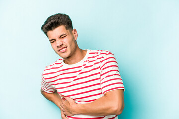 Young caucasian man isolated on blue background having a liver pain, stomach ache.