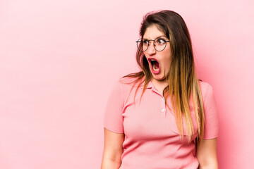 Young caucasian woman isolated on pink background shouting very angry, rage concept, frustrated.