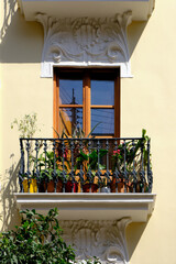 Close-up of a beautiful apartment building with wooden frame window and a balcony with plants in Valencia, Spain.