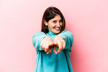 Young caucasian woman isolated on pink background pointing to front with fingers.