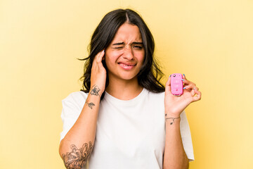 Young hispanic woman holding a keys car isolated on pink background covering ears with hands.