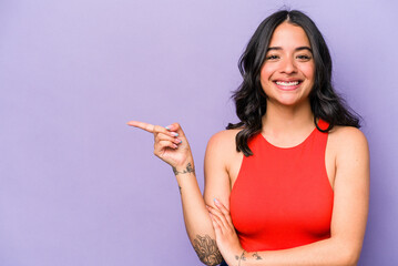 Young hispanic woman isolated on purple background smiling cheerfully pointing with forefinger away.