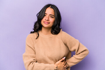 Young hispanic woman isolated on purple background having a liver pain, stomach ache.