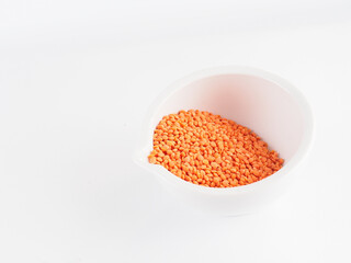 Red lentils in a white bowl on a white background. Red lentils macro