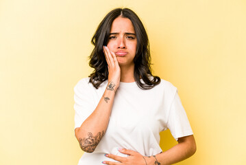 Young hispanic woman isolated on yellow background blows cheeks, has tired expression. Facial expression concept.