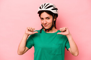 Young caucasian woman wearing helmet isolated on pink background feels proud and self confident, example to follow.
