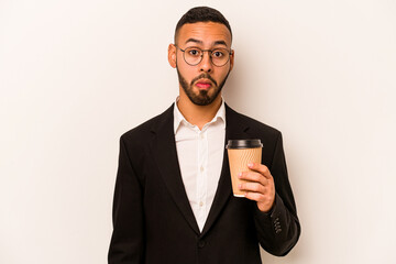 Young business hispanic man holding takeaway coffee isolated on white background shrugs shoulders...