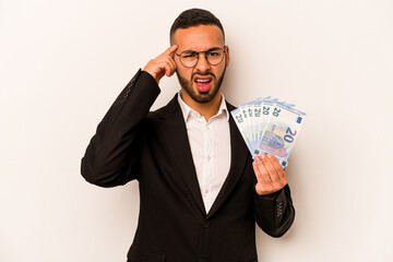 Young business hispanic man holding banknotes isolated on white background showing a disappointment gesture with forefinger.