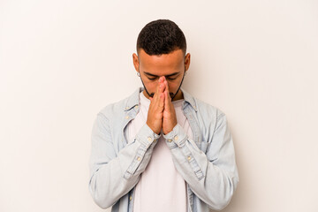 Young hispanic man isolated on white background praying, showing devotion, religious person looking...