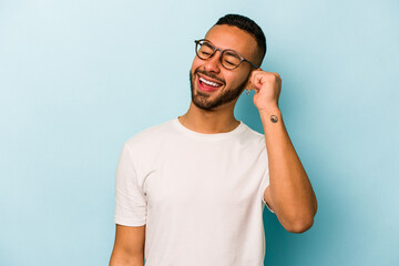 Young hispanic man isolated on blue background celebrating a victory, passion and enthusiasm, happy expression.