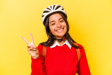 Young student hispanic woman wearing a bike helmet isolated on yellow background joyful and...