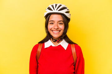 Young student hispanic woman wearing a bike helmet isolated on yellow background happy, smiling and cheerful.